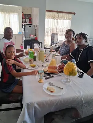 a group of people sitting around a table with food at Casa dos Amigos in Calheta de São Miguel