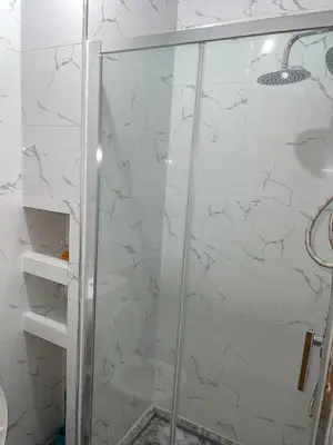 a bathroom with a shower with a glass door at madison place in Praia