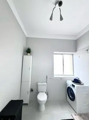 a bathroom with a toilet and a washing machine at MorabezaHome- Apartment Tati in Mindelo