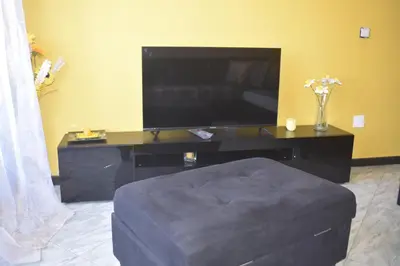 a living room with a flat screen tv and a ottoman at De Pina Apartments in Pedra Badejo