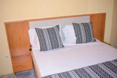 a bed with a wooden headboard and two pillows at De Pina Apartments in Pedra Badejo
