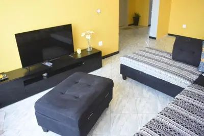 a living room with a couch and a chair and a tv at De Pina Apartments in Pedra Badejo