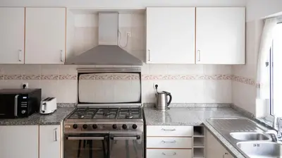 a kitchen with white cabinets and a stove and a sink at 2 bdr apt in Palmarejo Baixo, near seafront - LCGR in Praia