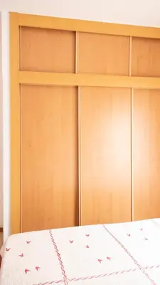 a bedroom with wooden closet doors and a bed at 2 bdr apt in Palmarejo Baixo, near seafront - LCGR in Praia