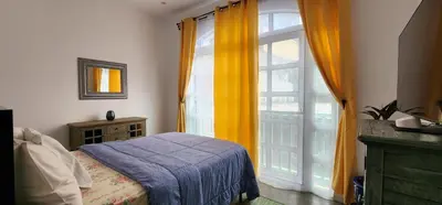 a bedroom with a bed and a large window at Casinha Nova - Comfort & Class in Fogo in São Filipe