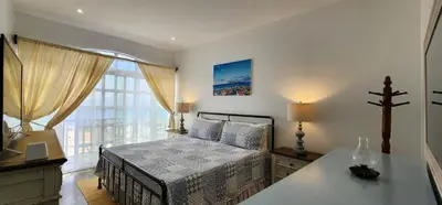 a bedroom with a bed and a table and a window at Casinha Nova - Comfort & Class in Fogo in São Filipe