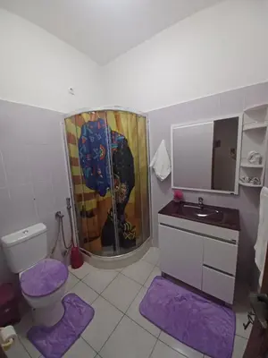 a bathroom with a toilet and a shower with purple mats at Repousando II in Ribeira Grande