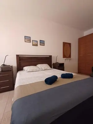 a bedroom with a large bed with two blue pillows on it at Casa Verde in Santa Maria