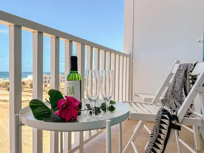 a table with a bottle of wine and glasses on a balcony at Papaya Apartments Boa Vista in Sal Rei