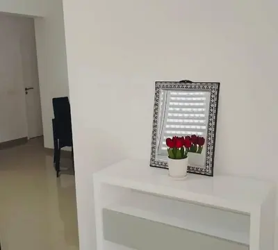 a white table with a mirror and a vase of flowers at Apartamento Da Costa in Mão para Trás