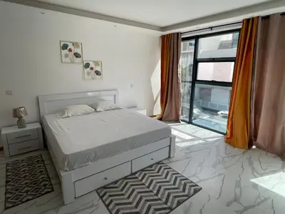 a white bedroom with a bed and a large window at Rosario’s Residence in Praia