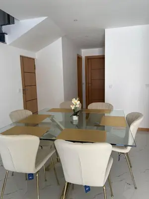 a dining room with a glass table and white chairs at Rosario’s Residence in Praia