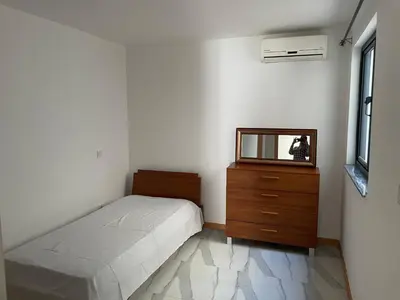 a bedroom with a bed and a dresser and a mirror at Rosario’s Residence in Praia
