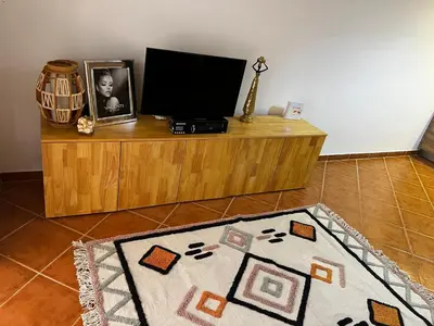 a desk with a television and a rug on the floor at Beira Mar AB2 in Santa Maria