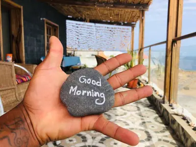a person holding a rock with good morning written on it at Get house kira in Cidade Velha