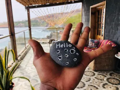 a hand holding a black rock with the word hello at Get house kira in Cidade Velha