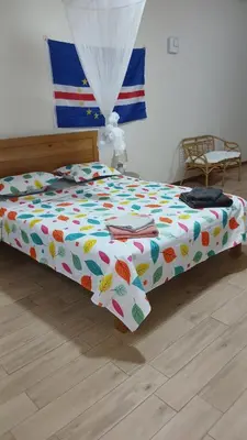 a bed with a colorful comforter on top of it at Get house kira in Cidade Velha