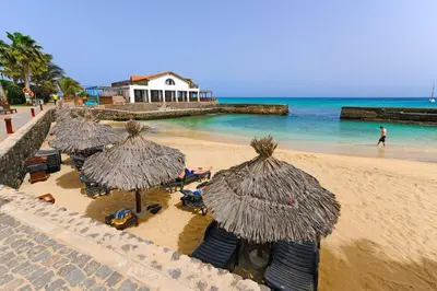 a group of chairs and umbrellas on a beach at T1 Vista Mar - Porto Antigo 3 in Santa Maria
