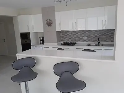 a kitchen with a white counter with three stools at Morabeza Deluxe view on the sea in Mindelo