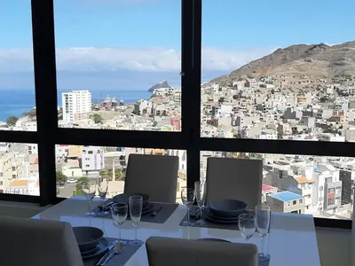 a table with wine glasses and a view of a city at Morabeza Deluxe view on the sea in Mindelo