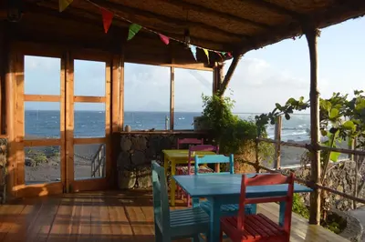 a table and chairs on a porch with a view of the ocean at Casa De France in Porto Novo