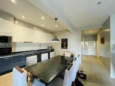 a kitchen with a dining table and white cabinets at Aparthotel Pilon T3 in Praia