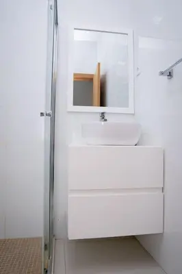 a white bathroom with a sink and a mirror at Apartamento das Flores 2 in Praia