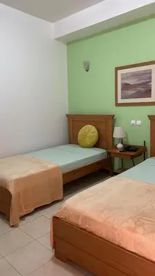 two beds in a room with green walls at Felicidade Hotel in Praia