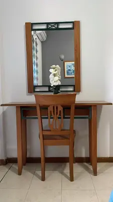 a wooden dressing table with a mirror and a vase of flowers at Felicidade Hotel in Praia
