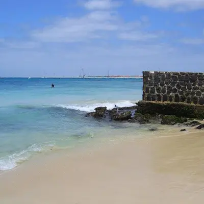a beach with a rock wall and the ocean at Vila Verde - Chez Val in Santa Maria