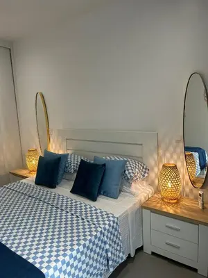 a bedroom with a bed with blue pillows and two mirrors at Ely's Place by the Sea in Praia Baixo