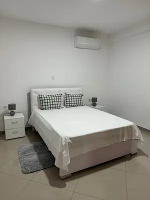 a white bedroom with a bed and two night stands at Holiday Apartments TF in Praia