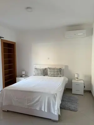 a white bedroom with a bed and two night stands at Holiday Apartments TF in Praia