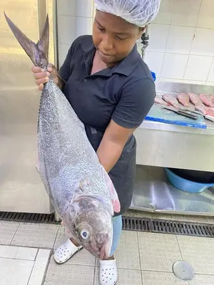 a woman holding a fish in a kitchen at Beramar Hotel in Praia