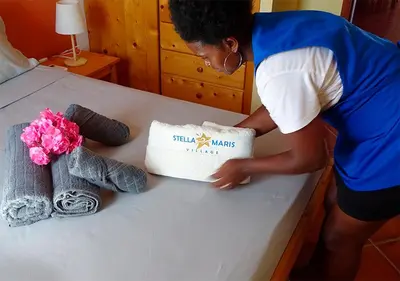 a woman is putting a pillow on a table at Appartamento Polvo. Stella Maris Exclusive in Calheta Do Maio