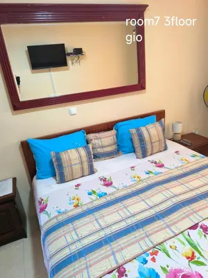 a bed with blue pillows and a tv on the wall at guesthouse emaly in Mindelo
