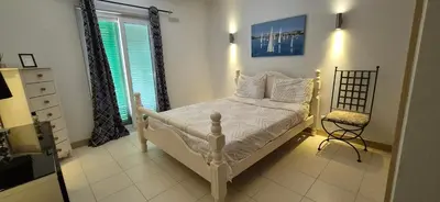 a bedroom with a white bed and a chair at SUNNY Apartment - SAL VILA VERDE - Cabo Verde in Santa Maria