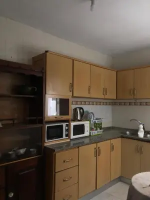 a kitchen with wooden cabinets and two microwaves at Simple sunlight apartment - Assomada in Assomada