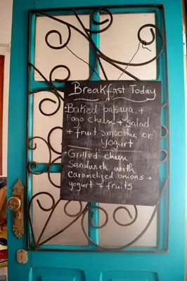 a chalkboard sign on a blue door with a menu at Syd's Guesthouse in Praia
