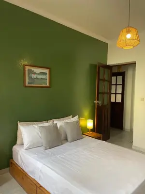 a bedroom with a white bed with a green wall at Syd's Guesthouse in Praia