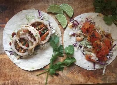 two tacos with onions and vegetables on a cutting board at Syd's Guesthouse in Praia