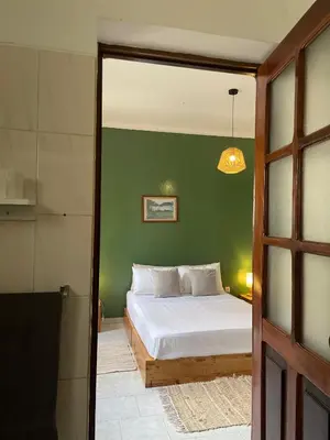 a bedroom with a bed and a green wall at Syd's Guesthouse in Praia