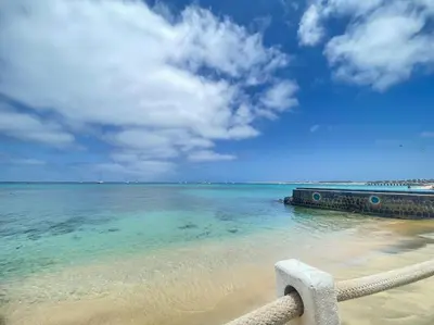 a view of the ocean from a beach with a bench at Salty Apartments in Santa Maria