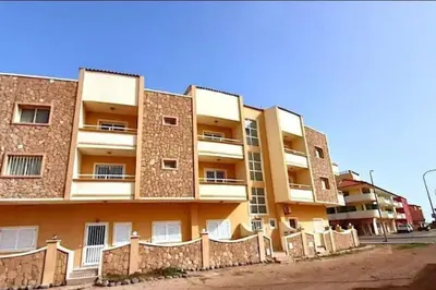 an apartment building with a fence in front of it at Salty Apartments in Santa Maria