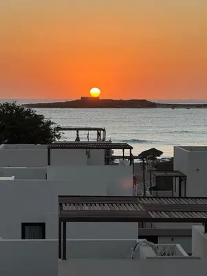 a sunset over the ocean with a pier and the ocean at Vila Cristina Alojamento, Praia Estoril, Boa Vista in Sal Rei