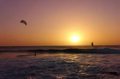 two people kite surfing in the ocean at sunset at Nagoia's place com varanda, piscina e super wi-fi in Santa Maria