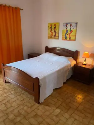 a bedroom with a large bed and two paintings on the wall at Muralha Rooms in Mindelo