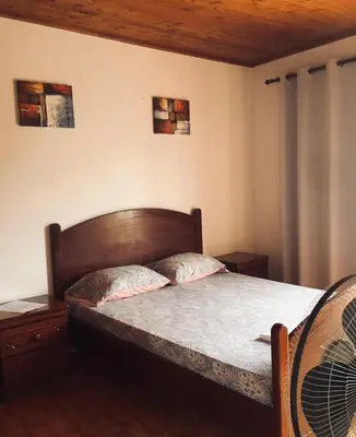 a bedroom with a bed with a wooden headboard at Muralha Rooms in Mindelo