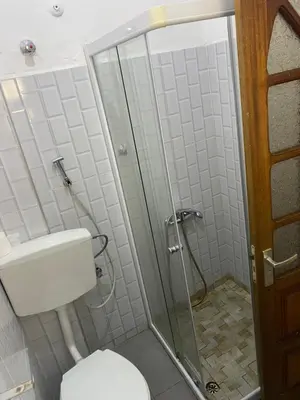 a bathroom with a toilet and a glass shower at Muralha Rooms in Mindelo