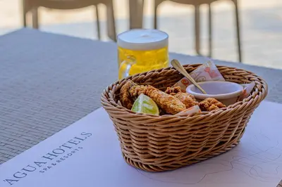a basket of food and a glass of beer on a table at Agua Hotels Sal Vila Verde in Santa Maria